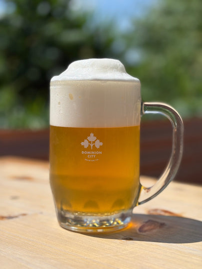 Glass of beer with foam on a wooden surface outdoors